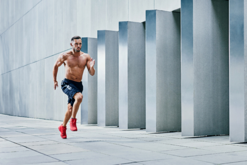 Handsome shirtless athlete jogging outside in modern urban setting